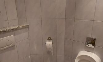 A small bathroom with modern tiles. Two sanitary facilities are visible: a toilet and a urinal.