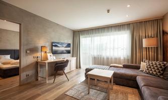 A modern room with a comfortable sofa and a desk. Large windows provide plenty of daylight.