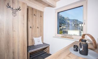 A cozy room with wood paneling and a window that offers a view of the mountains. An elegant decoration and a seating area complete the ambiance.