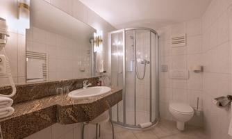 A modern bathroom with a shower, sink, and large mirror. The walls are brightly tiled, and the decor looks clean and inviting.