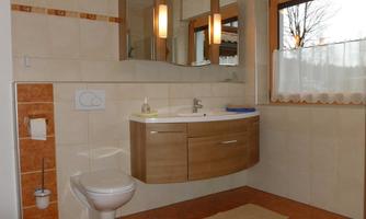 A modern bathroom with a wooden sink and a large mirror. The window offers a view of the outdoors and the floor is tiled.