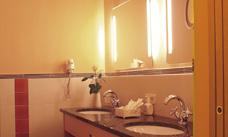 A modern bathroom with a sink and a large mirror. The walls are designed in warm colors and there are sanitary facilities.