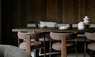 A stylish dining room with a wooden table and modern chairs. Plates and decorative objects are on the table.