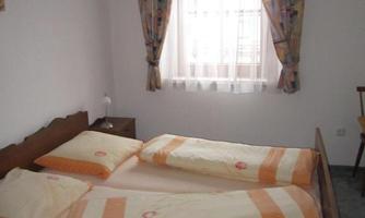 A simple bedroom with a double bed and colorful curtains. The room has a window that lets in daylight.