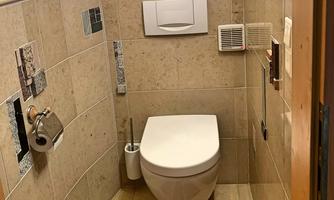 A simple bathroom with a modern toilet. The walls are designed with light tiles and decorative elements.