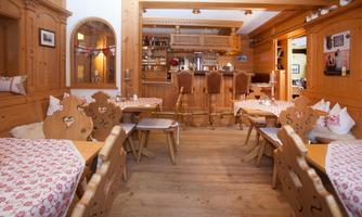 A cozy restaurant with wooden furniture and traditional table decor. The bar in the background invites you to stay.