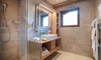 A modern bathroom with a glass shower and a large mirror. Bright tiles and wooden accents create an inviting atmosphere.