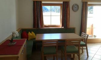 A cozy room with a large table and a seating area. Bright windows provide plenty of natural light.
