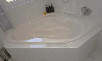 An elegant, oval bathtub in a modern bathroom. In the background, personal care products and a bright environment are visible.