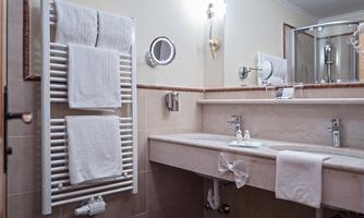 A modern bathroom with a towel warmer and sink. The walls are designed in neutral tones and there is a privacy screen for the shower.