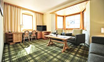 A bright living and bedroom with large windows and a cozy atmosphere. The furnishings consist of a sofa, a table, and modern furniture.