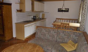 A cozy living kitchen with a sofa, a table, and simple kitchen furnishings. The walls are light, and the atmosphere is inviting.