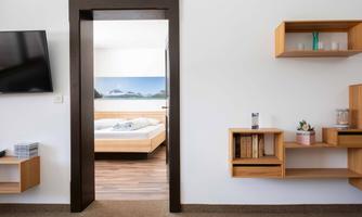 A modernly designed room with a view of a bedroom. On the left side, there is a television and shelves on the wall.