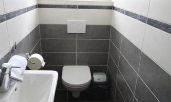 A small, modern bathroom with tiles in black and white. It features a sink, a toilet, and a window for natural light.