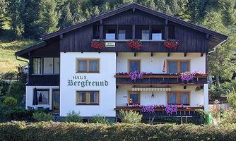 A charming mountain house named "Haus Bergfreund". It has a lovely garden and balconies full of flowers.