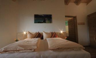 A cozy room with a large bed and soft lighting. On the wall hangs a picture that contributes to the relaxing atmosphere.