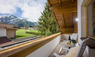 A cozy balcony with a view of the mountains. On the table are drinks and a blanket to enjoy the view.