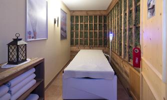 A quiet wellness area with a massage bed and soft lighting. The walls are designed with natural materials that create a relaxing atmosphere.