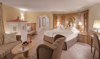 A cozy hotel room with a large double bed and stylish wooden furniture. The decor is warm and inviting, perfect for a relaxing stay.