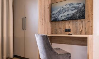 A modern room with a desk and a TV on the wall. The wood paneling and the gray chair give the space a cozy atmosphere.