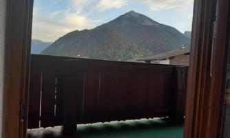 A view from a balcony of a majestic mountain. The sky is clear with a few clouds.