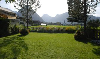 A green garden overlooking mountains and meadows. The surroundings feel peaceful and idyllic.