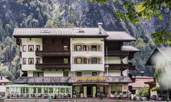 A charming hotel nestled in the mountains. It offers an inviting facade and a view of the surrounding nature.