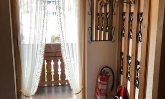 A bright hallway with an open window through which light streams. Coat hooks hang on the wall and a fire extinguisher is standing by.