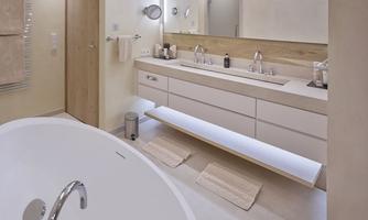 A modern bathroom with a freestanding bathtub and a bright vanity. The walls are painted in neutral colors, and there is a large mirror above the sink.