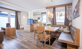 A modernly furnished living space with a dining area and a small kitchen. Light colors and wooden details create an inviting atmosphere.