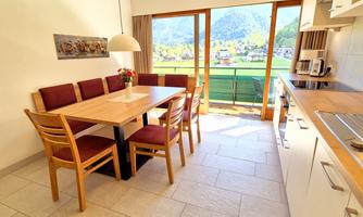 A modern dining room with a large table and chairs. Large windows provide a view of the surrounding landscape.