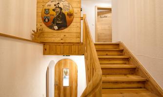 An inviting hallway with a wooden staircase and a decorative wall mural. The walls are light, and a door leads to another room.
