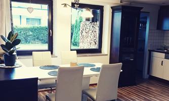 An inviting dining area with a table and four chairs. Bright walls and large windows bring a lot of light into the room.