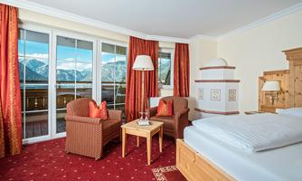 A cozy room with two armchairs and a small table. Large windows offer a wonderful view of the mountains.