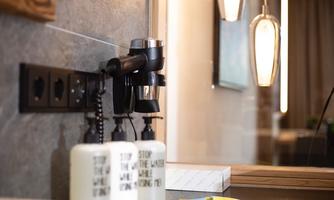 A modern bathroom with a kettle and elegant cosmetic bottles. In the background, stylish lamps and an appealing wall design can be seen.