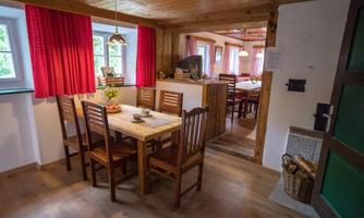 A cozy dining area with a wooden table and chairs. The red curtains and warm wood give the room an inviting atmosphere.
