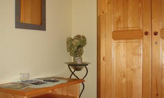 A cozy room with wooden furniture and a mirror. On a small table, there are flowers and an information brochure.