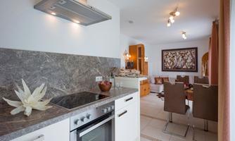A modern kitchen with bright furniture and an elegant countertop. The space is open and leads to a cozy dining area.