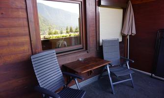 A cozy balcony with two chairs and a small table. In the background, there is a view of the mountains.