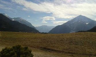 A wide meadow with mountains in the background and a clear sky. The scene radiates tranquility and a connection to nature.