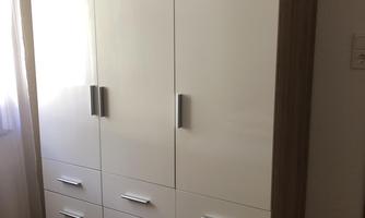 A modern cabinet with white doors and wooden accents. It has several compartments and drawers for storage.