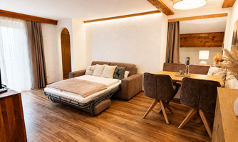 A modern living room with a sofa and a dining table. The wood and fabric elements create a cozy atmosphere.