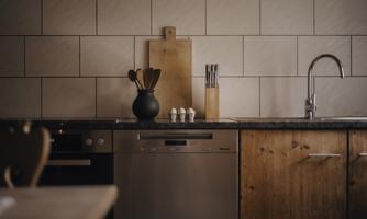 A modern kitchen with wood and stainless steel surfaces. On the countertop are cooking utensils and a cutting board.