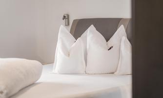 A cozy bed with decorative pillows in white. The entire surroundings feel modern and inviting.