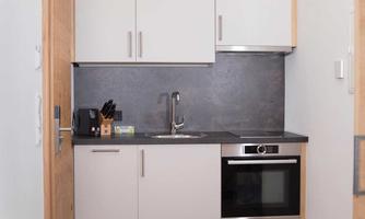 A modern kitchen corner with bright cabinets and stainless-steel appliances. The kitchen is compact and functionally designed.