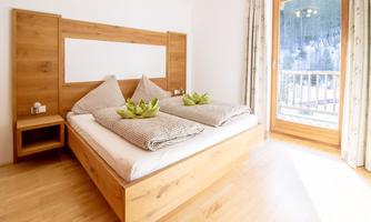 A bright bedroom with a wooden bed and comfortable pillows. Through the window, there is a beautiful view of nature.