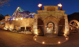 An impressive building with a large archway and modern glass elements. The outdoor area is well-lit and conveys an inviting atmosphere at night.