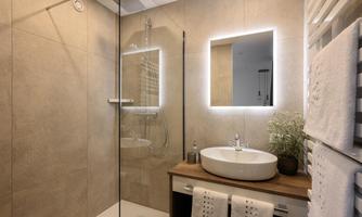 A modern bathroom with a glass shower and an elegant sink. On the wall, there is a illuminated mirror and decorative towels.