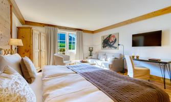 A bright and cozy room with two beds and a modern television. The large window front offers a beautiful view and the space is stylishly furnished.