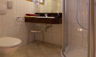 A modern bathroom with a shower and sink. Bright tiles and a window create a friendly atmosphere.